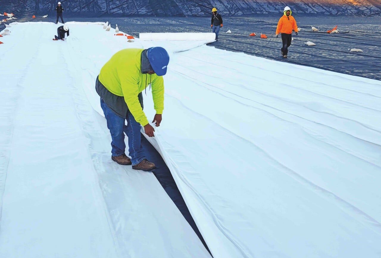 A man laying geosynthetic drainage solution , DrainTube, at a mine site.